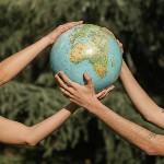 Mains et bras de deux personnes qui tiennent un globe terrestre.