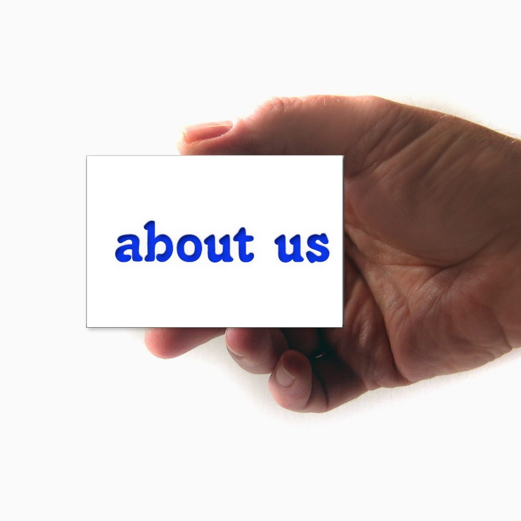 Un main présente un carton sur lequel est inscrit About us.