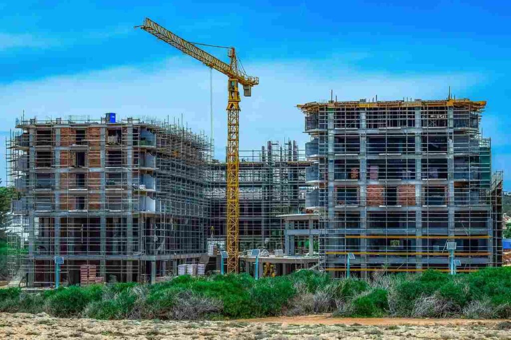 Un chantier de construction d'immeuble avec une grue au premier plan.